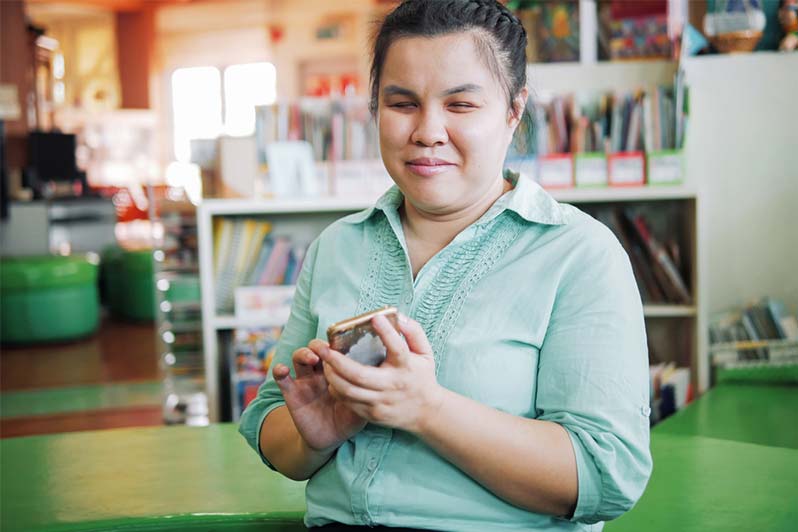 A blind woman using a smart phone. She has a look of satisfaction on her face.